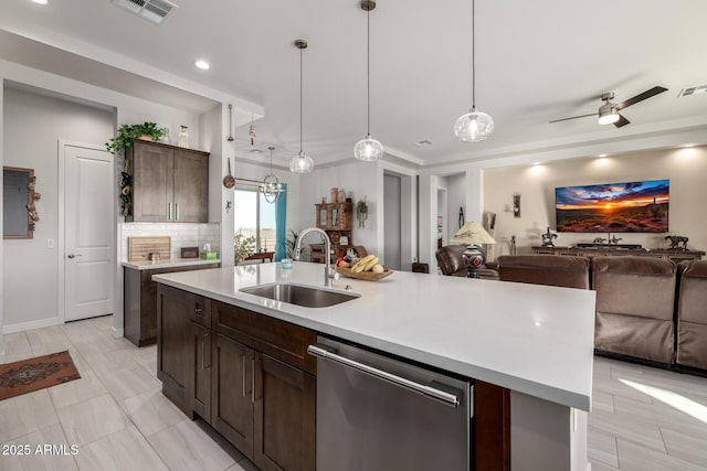kitchen with stainless steel dishwasher, visible vents, a sink, light countertops, and open floor plan