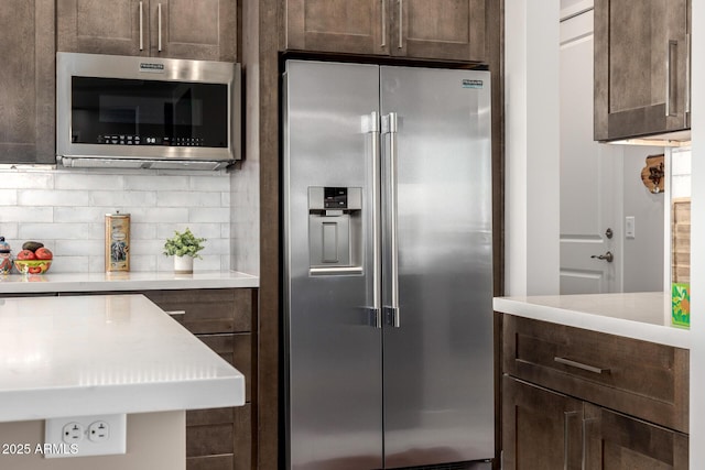 kitchen with tasteful backsplash, light countertops, dark brown cabinetry, and stainless steel appliances
