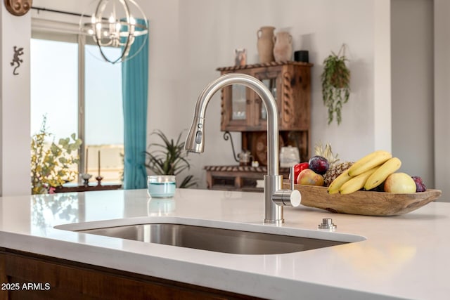 details featuring a chandelier, light countertops, a sink, and hanging light fixtures