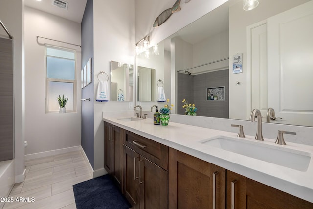 bathroom featuring a sink, visible vents, baseboards, and walk in shower