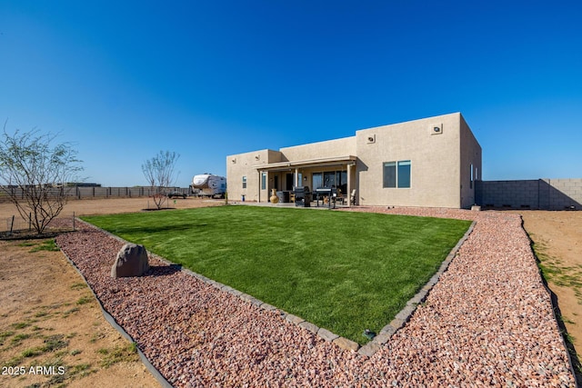 rear view of house with a patio, stucco siding, a fenced backyard, and a yard