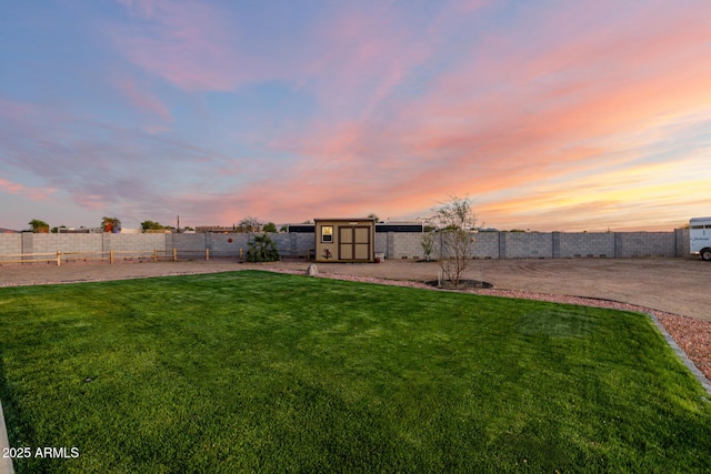 view of yard with an outbuilding, a fenced backyard, and a shed