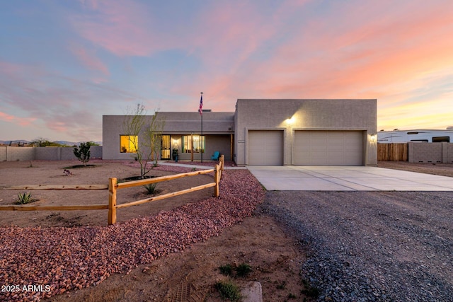 view of front of property with a garage, fence, concrete driveway, and stucco siding