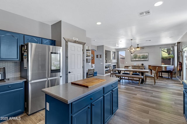 kitchen with light wood finished floors, smart refrigerator, tasteful backsplash, blue cabinetry, and visible vents