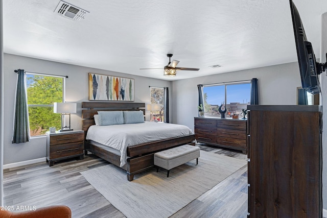 bedroom with visible vents, baseboards, ceiling fan, and light wood-style floors