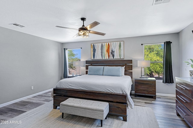 bedroom featuring visible vents, wood finished floors, multiple windows, and baseboards
