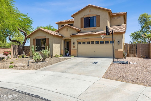 mediterranean / spanish home with a garage, driveway, a tiled roof, stucco siding, and fence