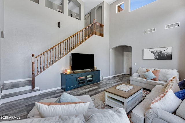 living room featuring visible vents, arched walkways, wood finished floors, and stairway