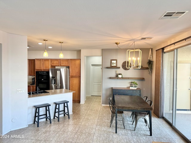 kitchen featuring stainless steel refrigerator with ice dispenser, a notable chandelier, a kitchen breakfast bar, and decorative light fixtures