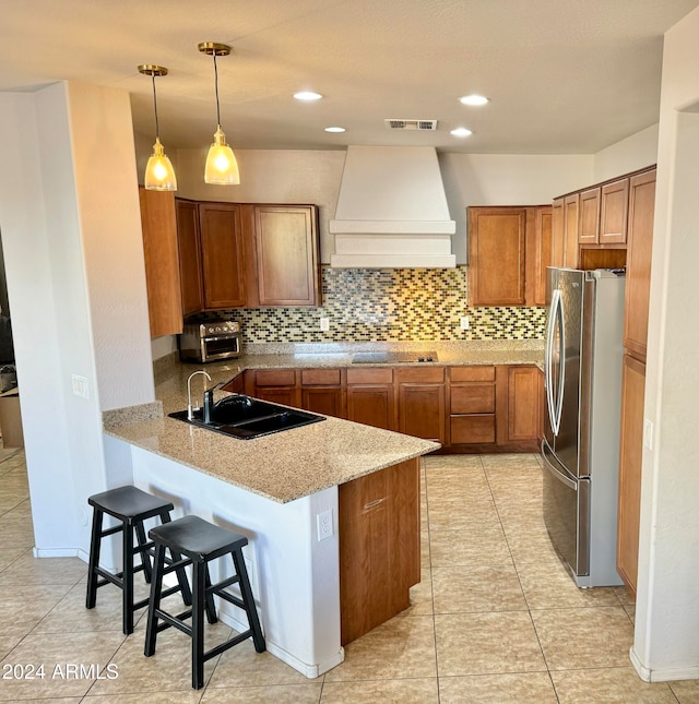 kitchen featuring sink, decorative light fixtures, stainless steel fridge, kitchen peninsula, and custom range hood