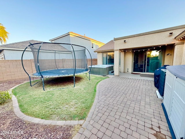 exterior space featuring a trampoline, a hot tub, and a patio