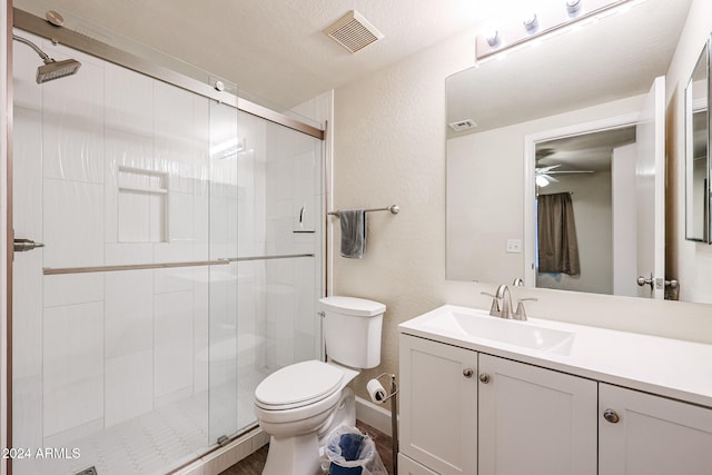 bathroom with vanity, ceiling fan, toilet, a textured ceiling, and an enclosed shower