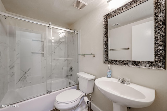 full bathroom featuring sink, bath / shower combo with glass door, and toilet