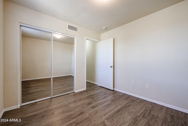 unfurnished bedroom with a closet and hardwood / wood-style flooring