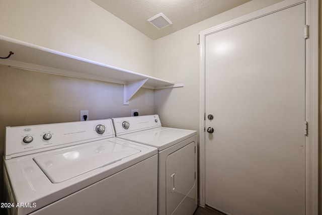 laundry area featuring washing machine and clothes dryer and a textured ceiling