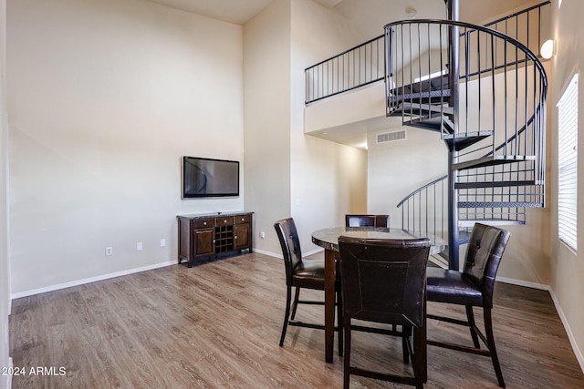 dining space with a towering ceiling, light hardwood / wood-style floors, and plenty of natural light