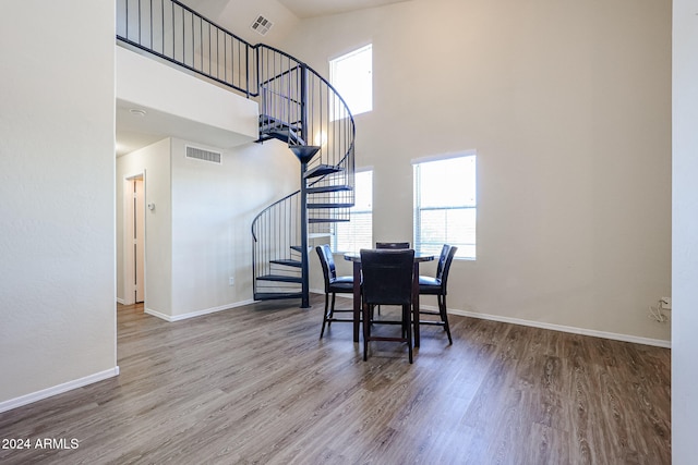 dining room with hardwood / wood-style floors and a towering ceiling