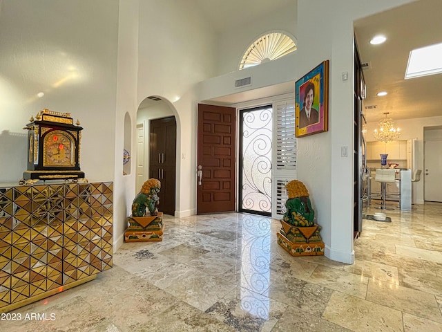 10068 E Turquoise Ave, Scottsdale, AZ 85258 - foyer entrance with baseboards, a high ceiling, arched walkways, visible vents, and a notable chandelier