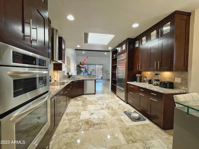 10068 E Turquoise Ave, Scottsdale, AZ 85258 - kitchen featuring light stone counters, tasteful backsplash, a peninsula, glass insert cabinets, and stainless steel appliances