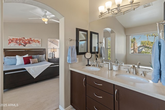 full bath with a wealth of natural light, ceiling fan with notable chandelier, and a sink
