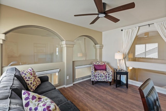 living room with baseboards, arched walkways, wood finished floors, and ceiling fan