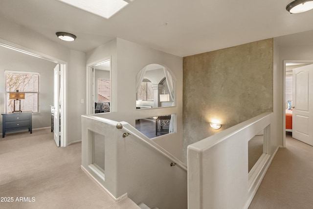 hallway featuring light colored carpet, an upstairs landing, and baseboards
