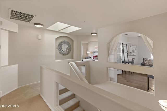 stairway with a skylight, baseboards, visible vents, arched walkways, and carpet