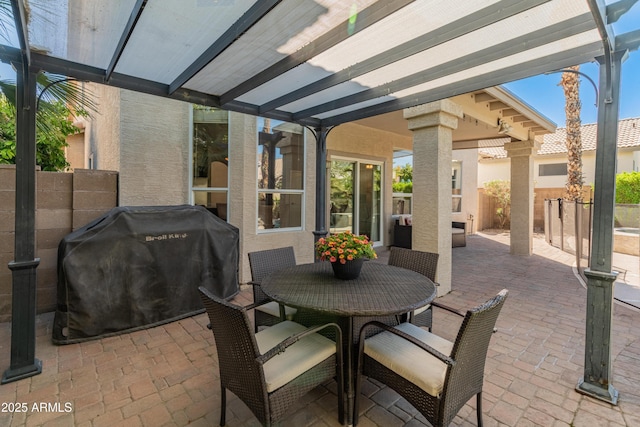 view of patio with grilling area, outdoor dining area, glass enclosure, and fence