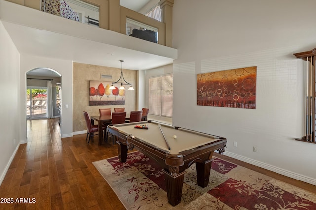 game room with pool table, baseboards, arched walkways, a towering ceiling, and dark wood-type flooring