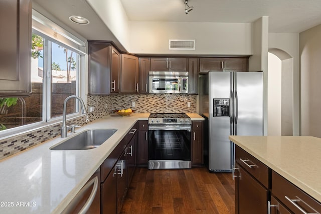 kitchen featuring visible vents, appliances with stainless steel finishes, dark brown cabinetry, dark wood-type flooring, and a sink