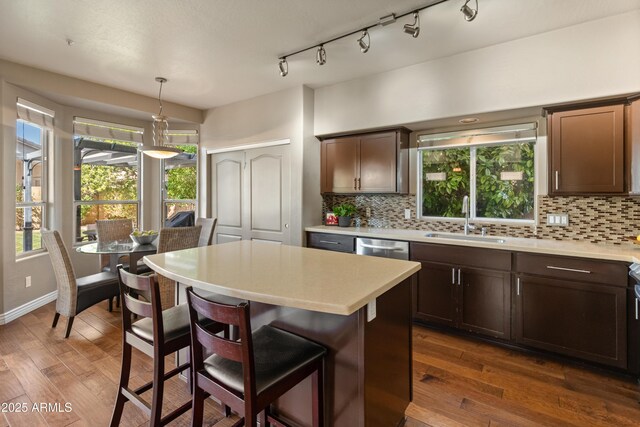 kitchen featuring dark wood-style flooring, light countertops, a sink, and backsplash