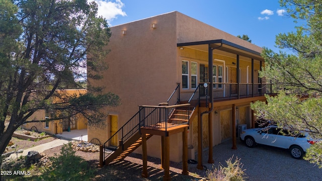 view of side of home with stucco siding and stairway