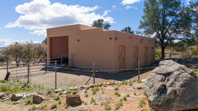 view of side of property featuring stucco siding, an outdoor structure, and an exterior structure