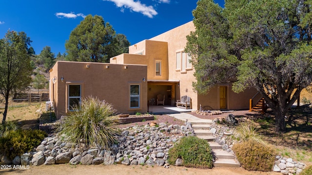 back of property featuring stucco siding, stairway, and a patio