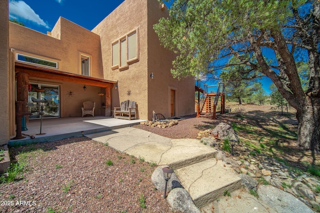 back of property featuring stucco siding, stairs, and a patio