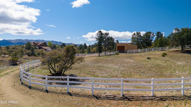 view of yard with an enclosed area, fence, a rural view, and a mountain view