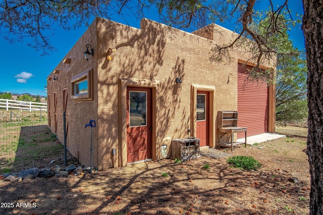 rear view of house featuring stucco siding and fence