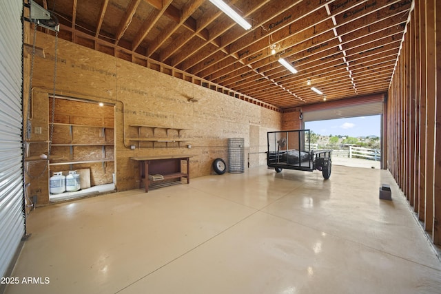 interior space featuring a garage, a towering ceiling, and concrete floors