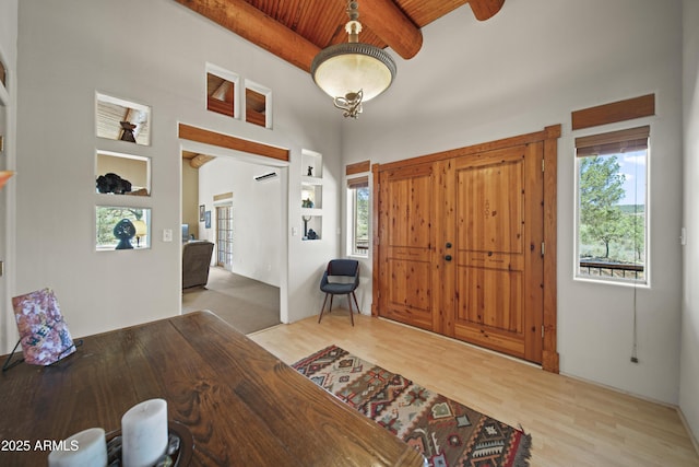 entrance foyer featuring light wood-type flooring, beam ceiling, wood ceiling, and a healthy amount of sunlight