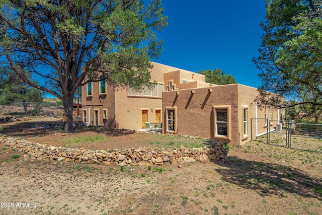 back of property with fence, a gate, and stucco siding