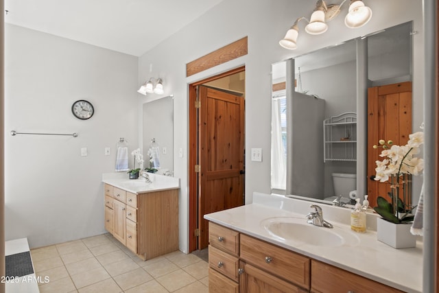 bathroom featuring two vanities, tile patterned flooring, toilet, and a sink