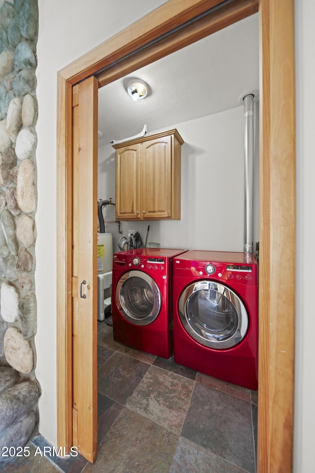 laundry room with washing machine and dryer, stone finish flooring, and cabinet space