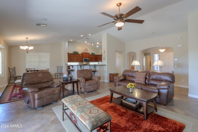 tiled living room with lofted ceiling and ceiling fan with notable chandelier