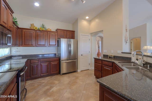 kitchen with high vaulted ceiling, stainless steel appliances, kitchen peninsula, sink, and light tile patterned flooring