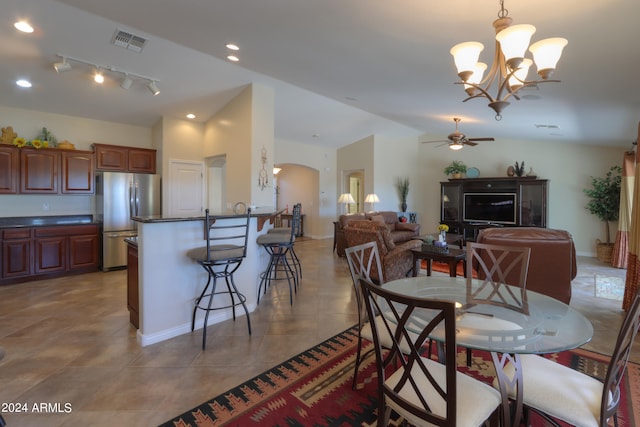 dining area featuring vaulted ceiling, ceiling fan with notable chandelier, and tile patterned floors