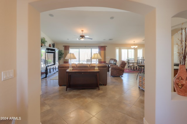 tiled living room with a healthy amount of sunlight and ceiling fan with notable chandelier