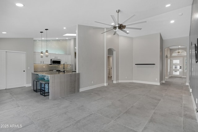 unfurnished living room featuring high vaulted ceiling and ceiling fan