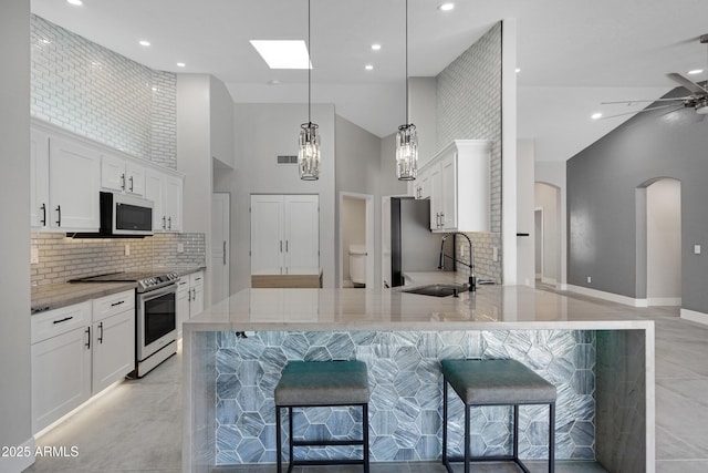 kitchen featuring hanging light fixtures, kitchen peninsula, white cabinets, and appliances with stainless steel finishes