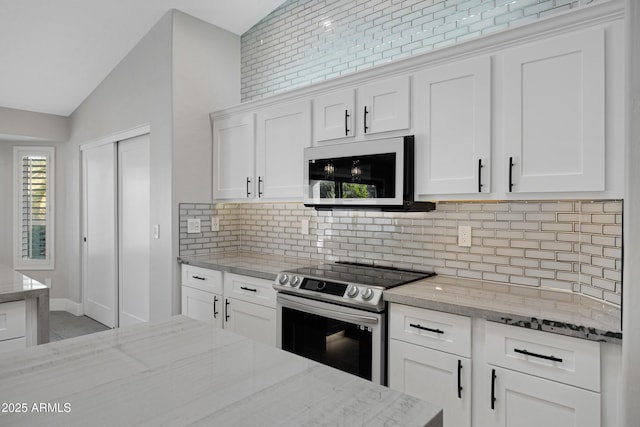 kitchen with electric stove, lofted ceiling, white cabinetry, backsplash, and light stone countertops