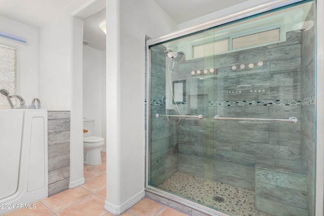 bathroom with tile patterned floors, toilet, and a shower with door